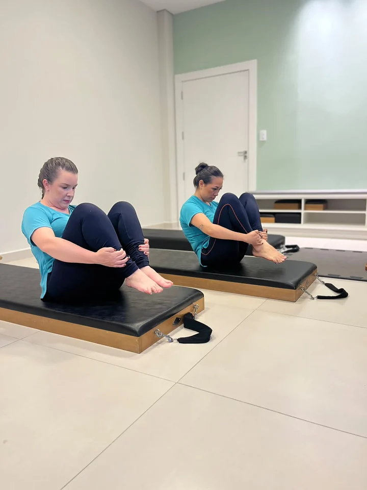 Duas alunas sentadas em colchonetes de Pilates no solo