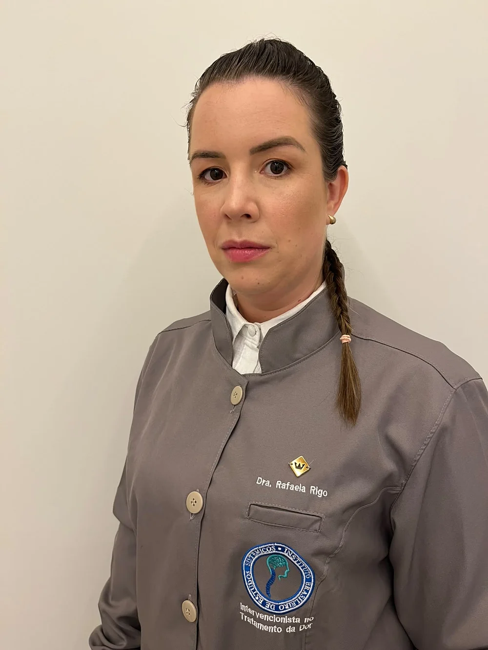 Dra. Rafaela Rigo de jaleco cinza com o bordado do seu nome
